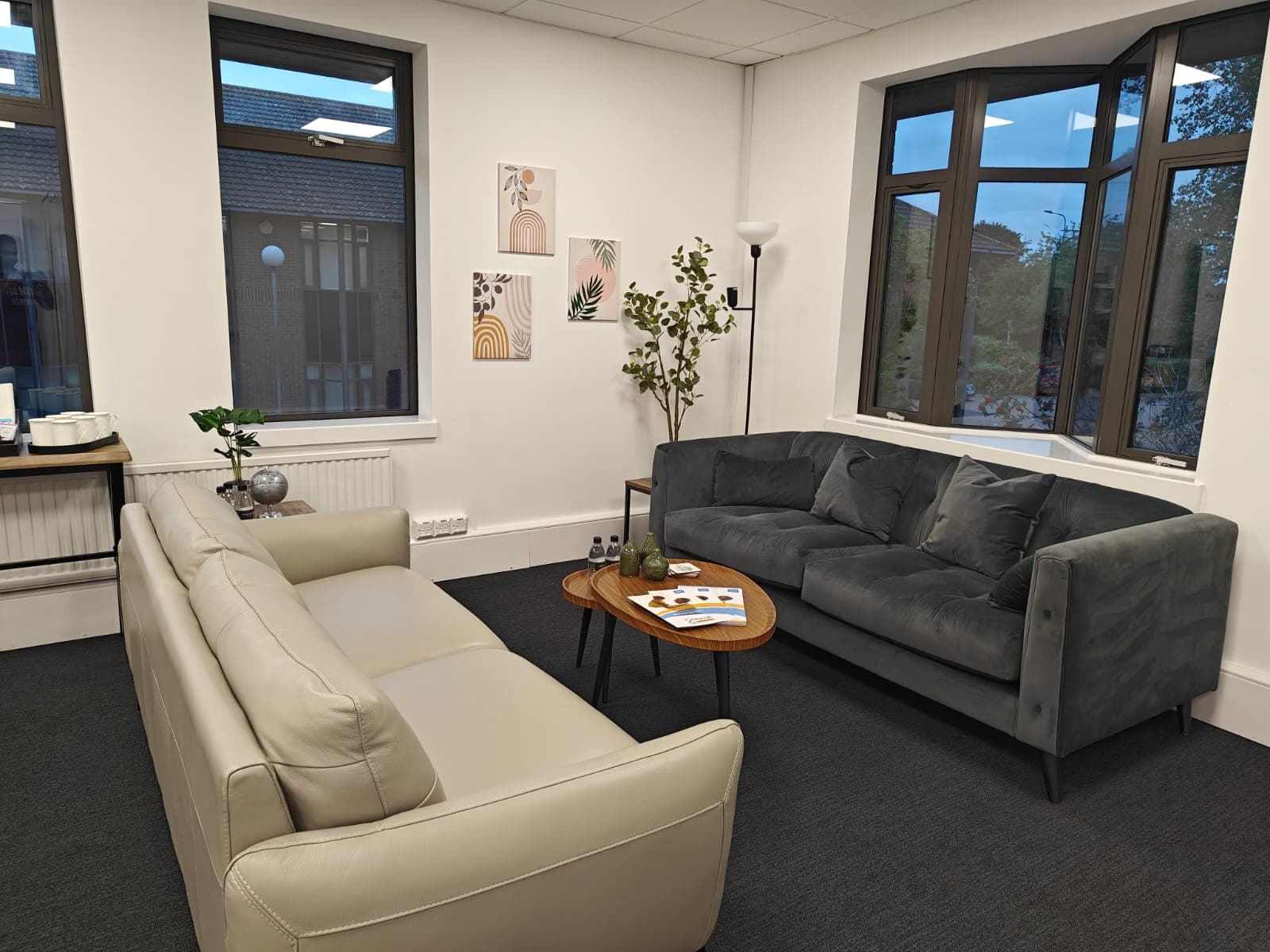 Modern lounge with a beige leather sofa, grey velvet couch, and wooden coffee table.